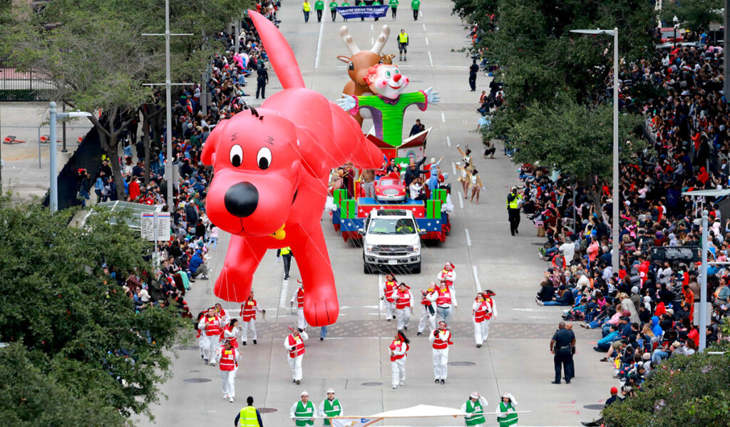 A parade float of Clifford the Big Red Dog moves through a Downtown street