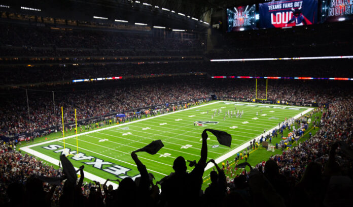 Fans waving flags are silhouetted before the Houston Texans field