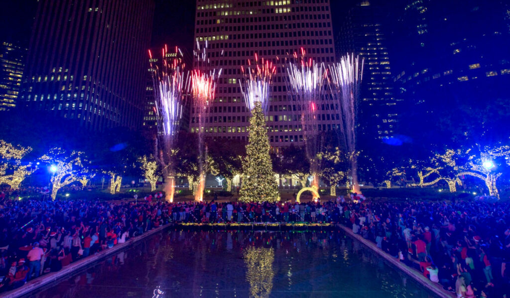A giant Christmas tree is lit up and fireworks go off behind it