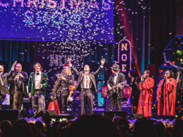 Confetti falling on a stage full of performers singing and playing instruments