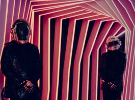 Two people in Daft Punk robot costumes standing in a hallway made of striped walls