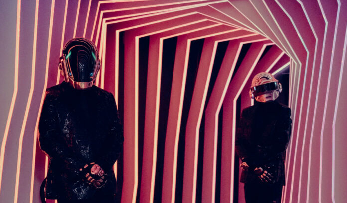 Two people in Daft Punk robot costumes standing in a hallway made of striped walls