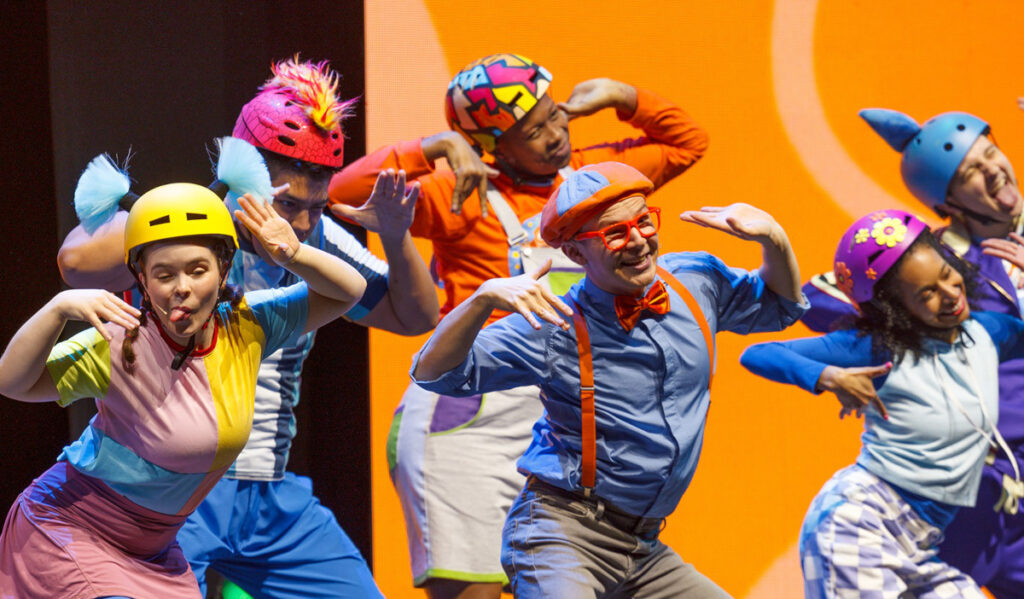 Performers in Blippi costumes dance and make silly faces