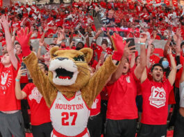 A Cougar mascot cheers with fans in the arena