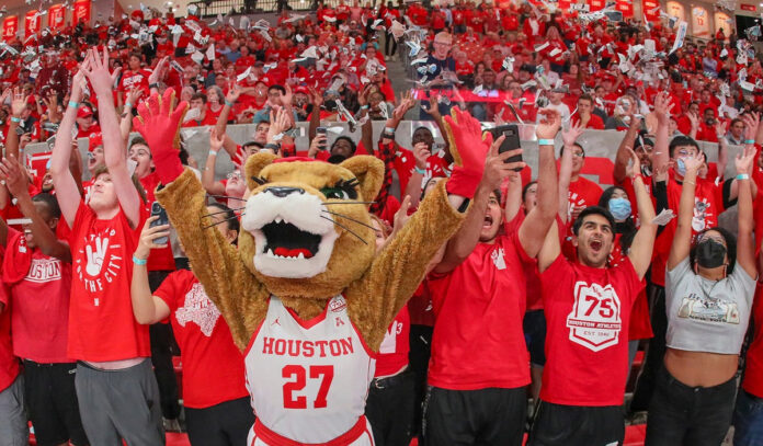 A Cougar mascot cheers with fans in the arena