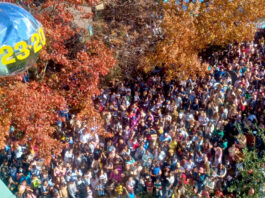 Crowds of people gather below a mirrored ball with "2023" numbers attached to it