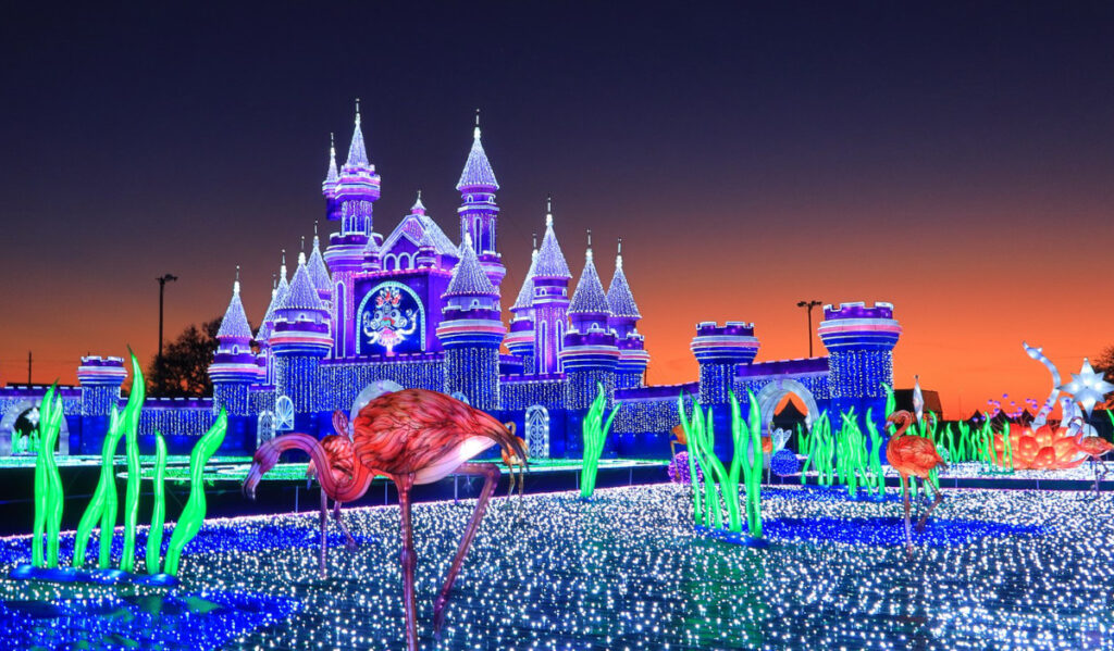 The castle entrance to Magical Winter Lights at sunset with flamingo lanterns and other decorations