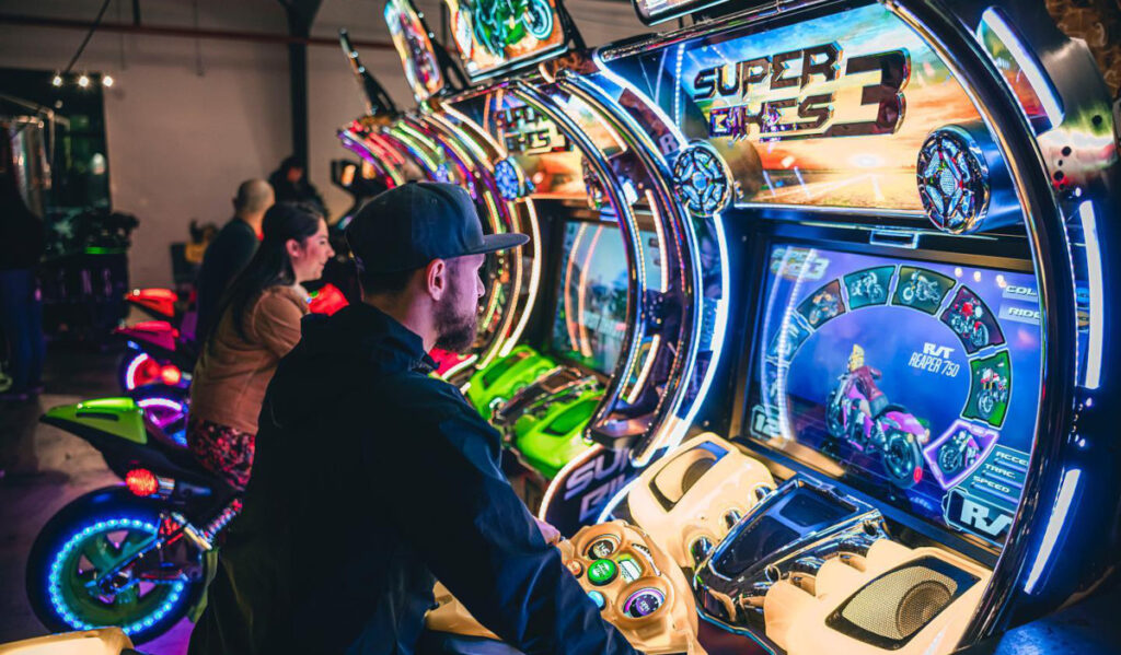 Two people on a motorcycle video game in an arcade