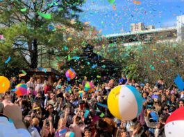 Confetti falls on a crowd of families and children, with bouncing beach balls