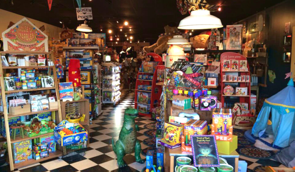 Interior of a toy store with a small dinosaur, books and other products on a black and white checkered floor