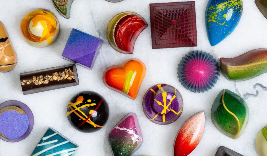 An array of colorful, shiny chocolates in various shapes and designs