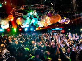 A nightclub with balloons, disco balls and a crowd of dancers