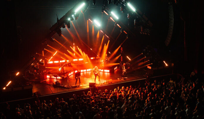 A band performing on stage with red lights on them