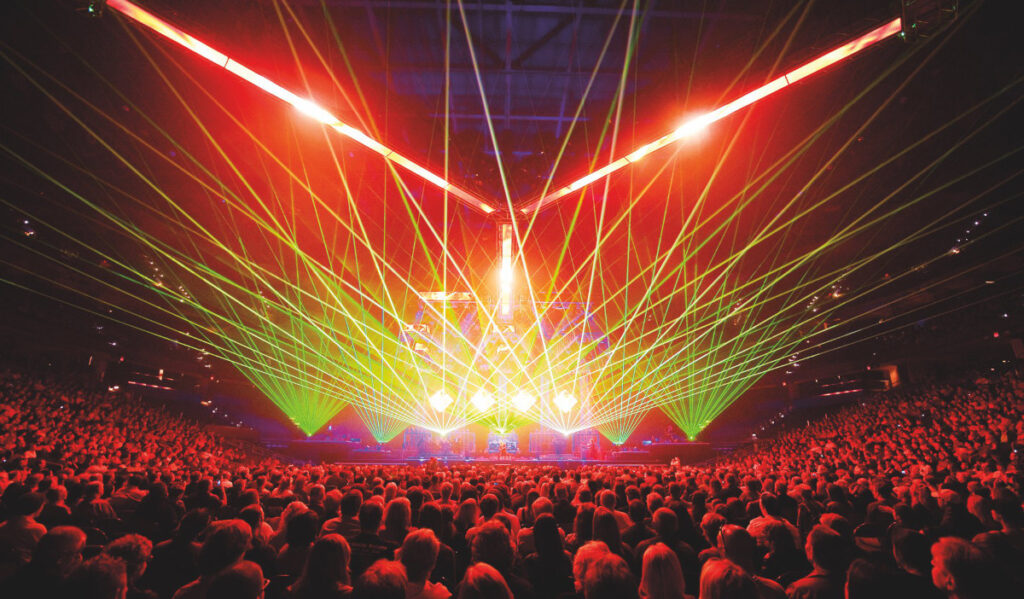 Green and red laser lights cast out from a stage over a crowd