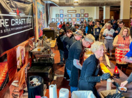 An indoor food festival with people sampling from bbq vendors