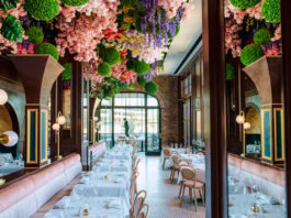 A dining room with extravagant bouquets of flowers hanging from the ceiling