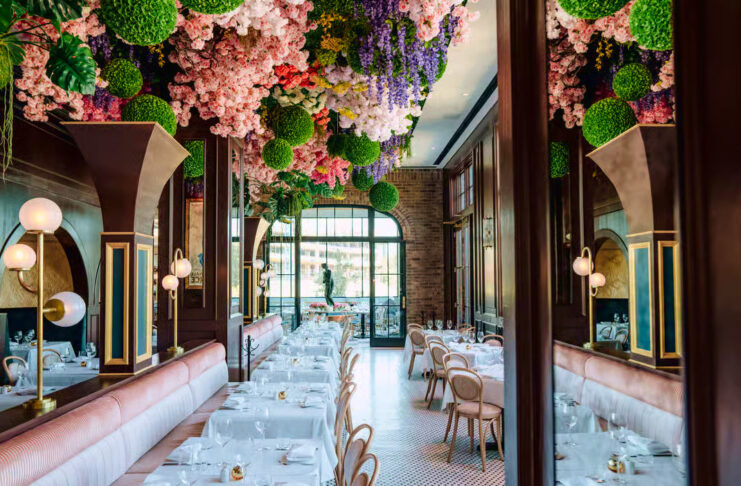 A dining room with extravagant bouquets of flowers hanging from the ceiling