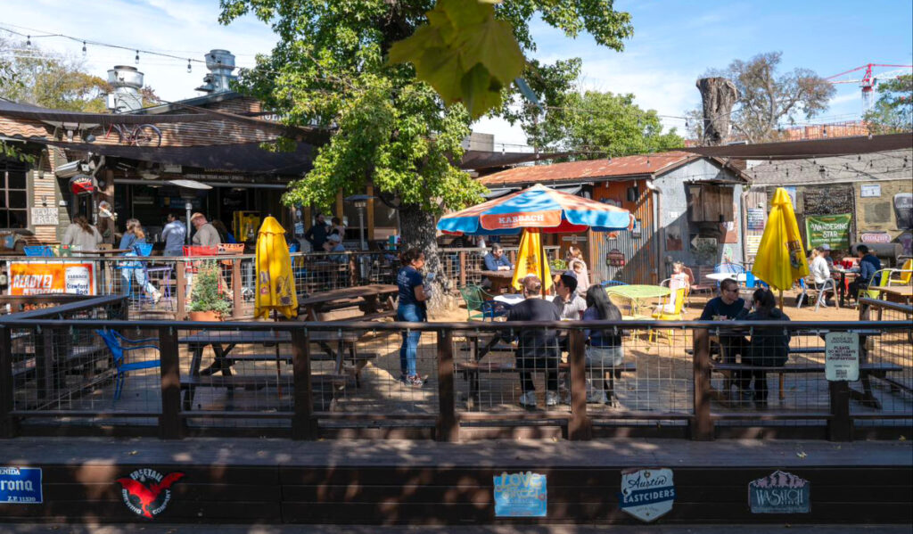 A spacious patio behind a restaurant with scattered groups sitting at tables