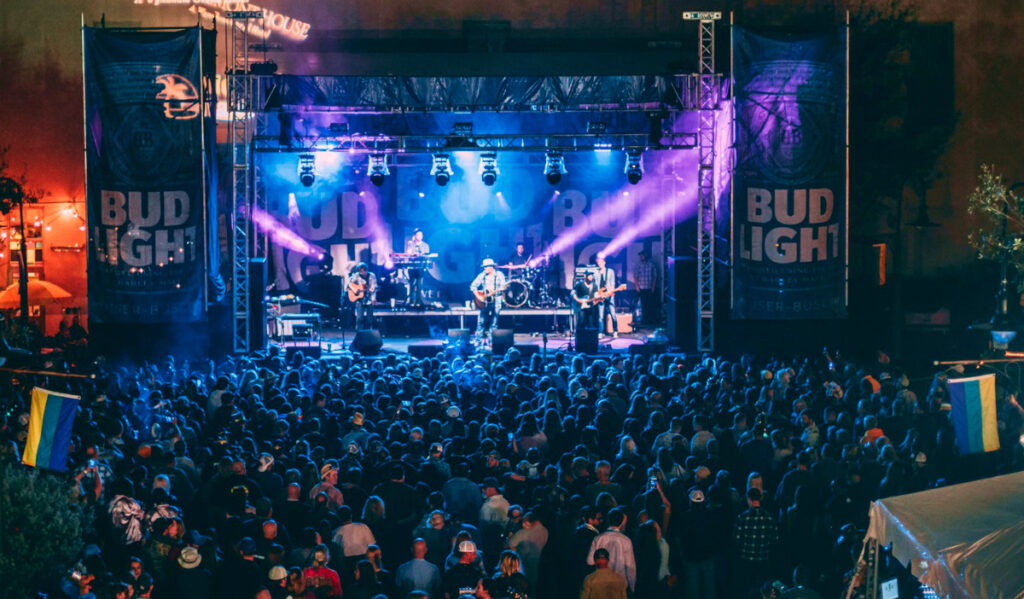 A distant view of a concert stage at night with blue and purple lights