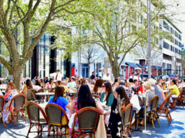 Crowds of people eating on an outdoor patio under trees