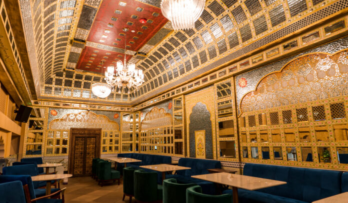 An elegant dining room with mirrored walls and ceilings, luxurious light fixtures and Indian-inspired decor