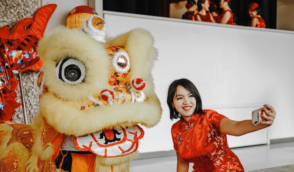 A woman posing with a Chinese lion for a photo