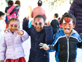 Three kids in face paint pose for the camera