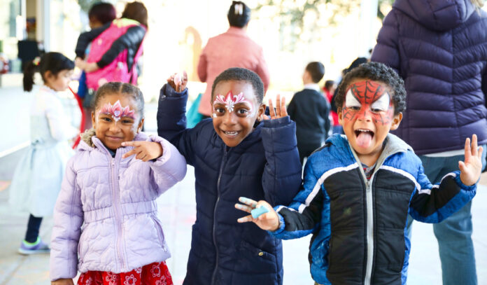 Three kids in face paint pose for the camera