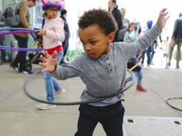 A toddler hula hoops with other children