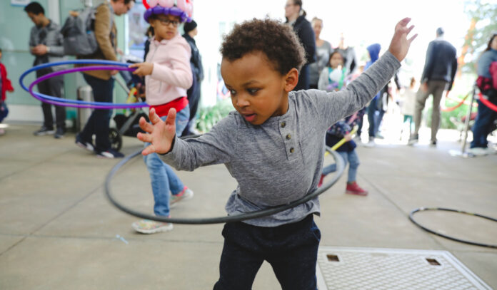 A toddler hula hoops with other children