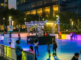 People roller skating in an outdoor rink with colorful lights