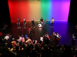 A stage with musicians playing to a crowd of families and kids