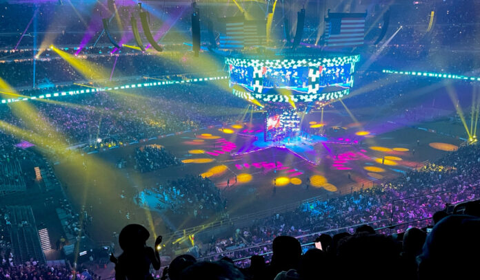 A view of a Houston Rodeo concert from the upper level with yellow, pink and teal lights flashing