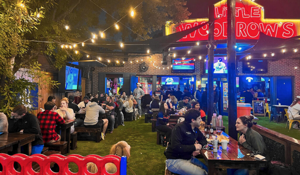 The outdoor patio of LIttle Woodrow's at night with crowds at tables