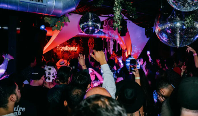 The interior of a night club with a crowd dancing below disco balls