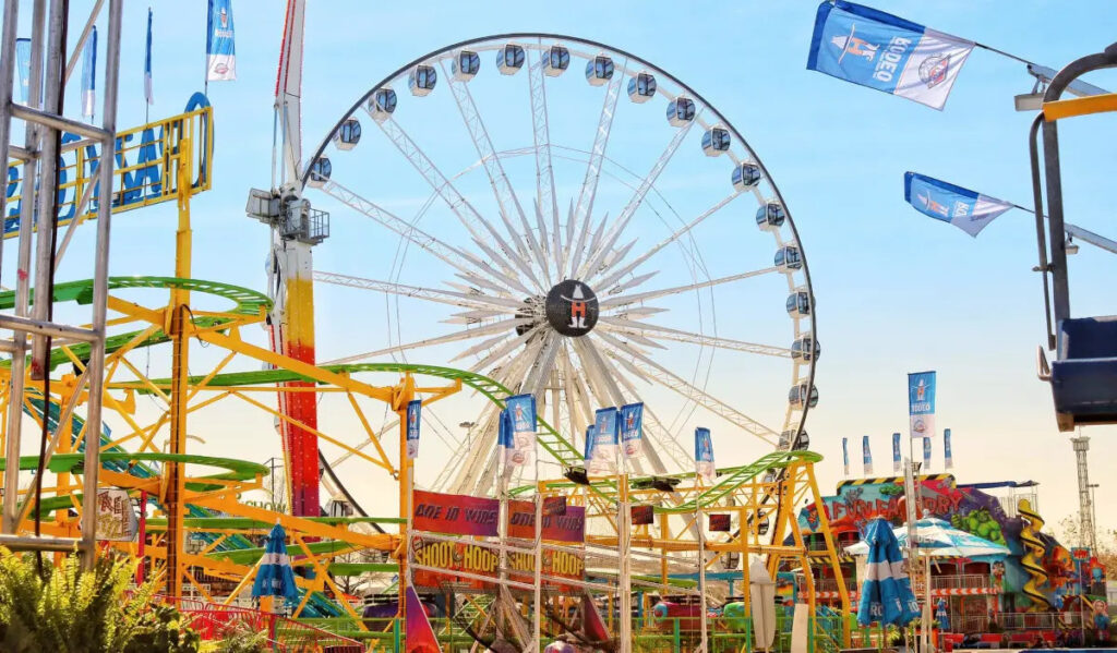 A Ferris Wheel surrounded by colorful roller coasters, carnival games and rides