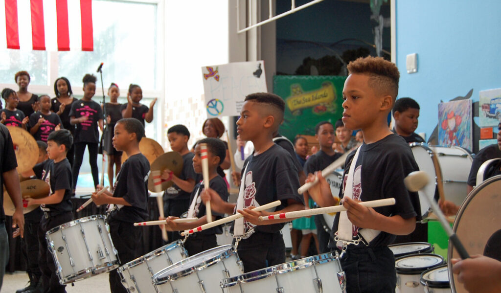 Children in a line playing on marching drums