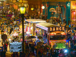 A Mardi Gras parade procession in Galveston led by a bus with a "Dance" banner and crowded by parade revelers