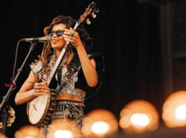 Valerie June holding a banjo while singing into a microphone