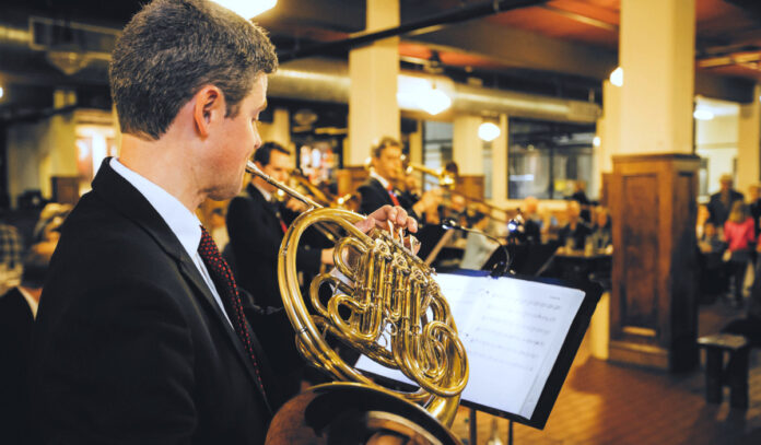 A horn player playing with other musicians in a beer hall