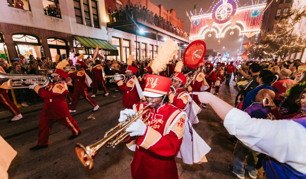 A marching band parades through Mardi Gras revelers