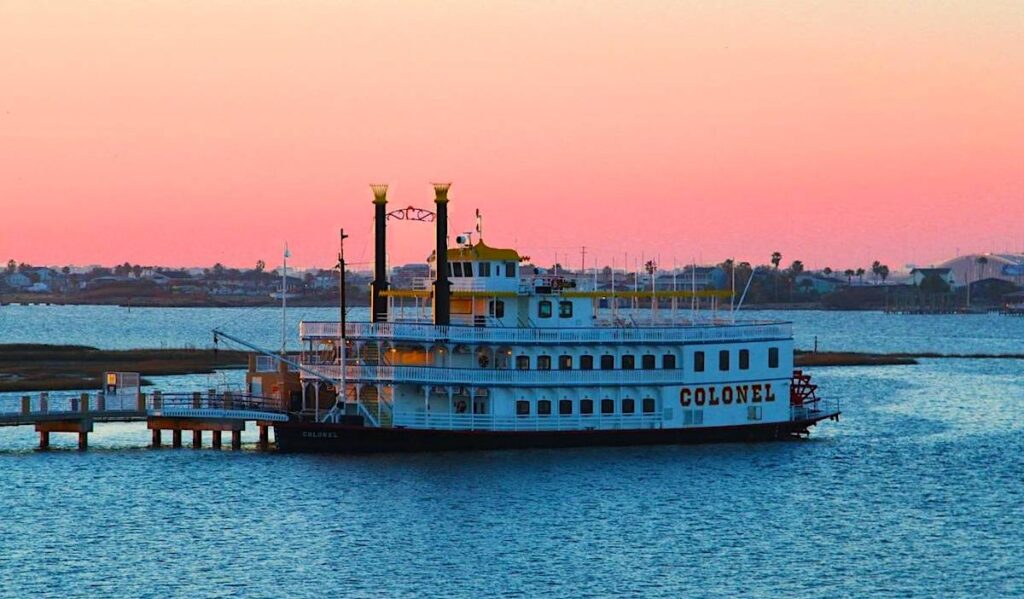 A paddlewheel boat docked at sunset