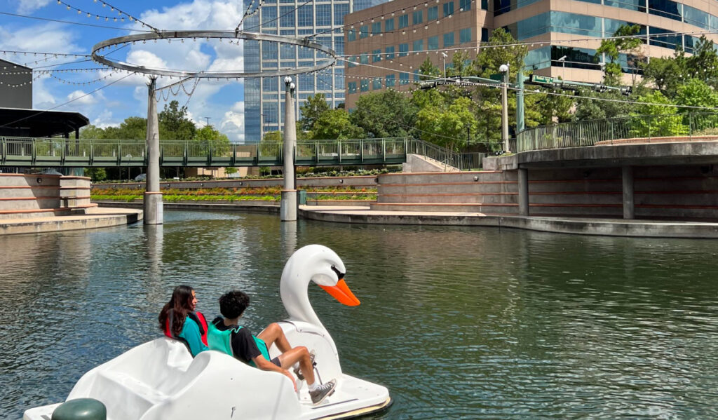 Two people paddling a swan boat in a waterway