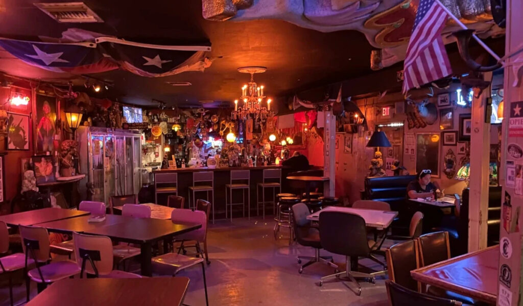 Dimly lit bar interior with empty chairs and tables and decor on the ceiling and walls