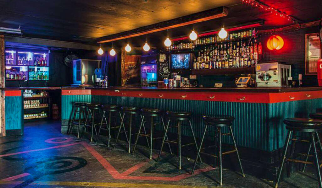 A bar interior with empty stools and overhead lights