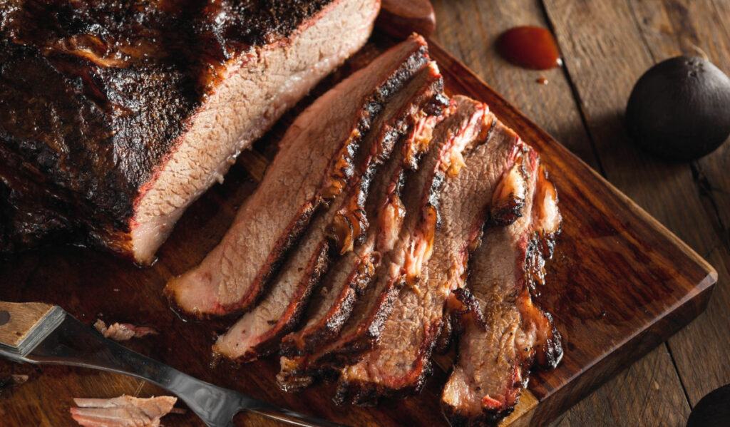 A mound of brisket on a cutting board with several slices