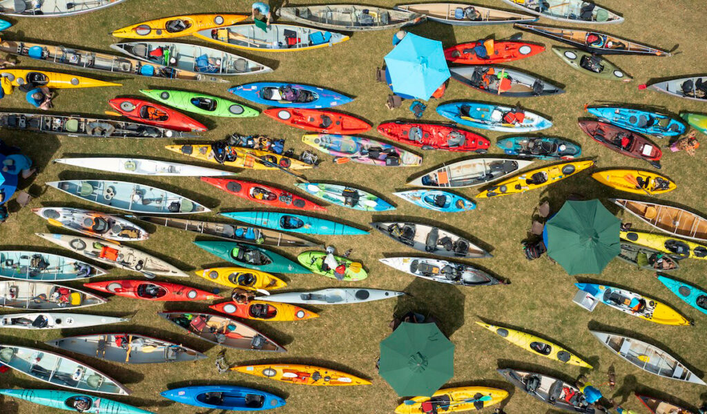 An overhead view of dozens of colorful kayaks on dry land