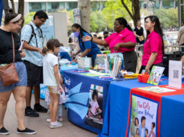 A child and two adults speaking with representatives at a book fair