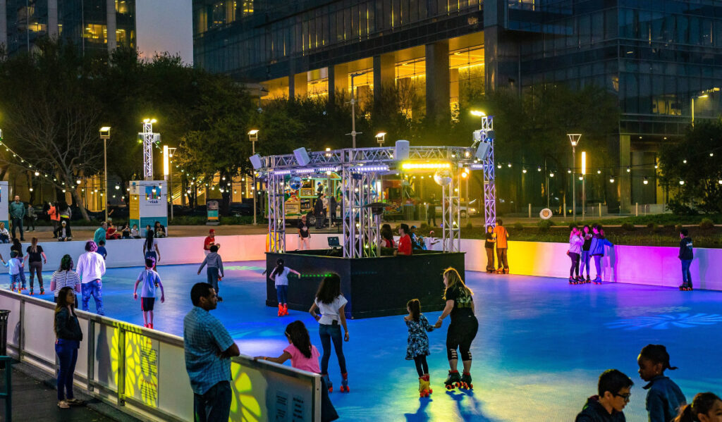 People roller skating in an outdoor rink with colorful lights