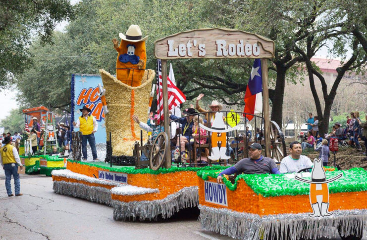 A green and orange parade float with a boot and Rodeo mascot